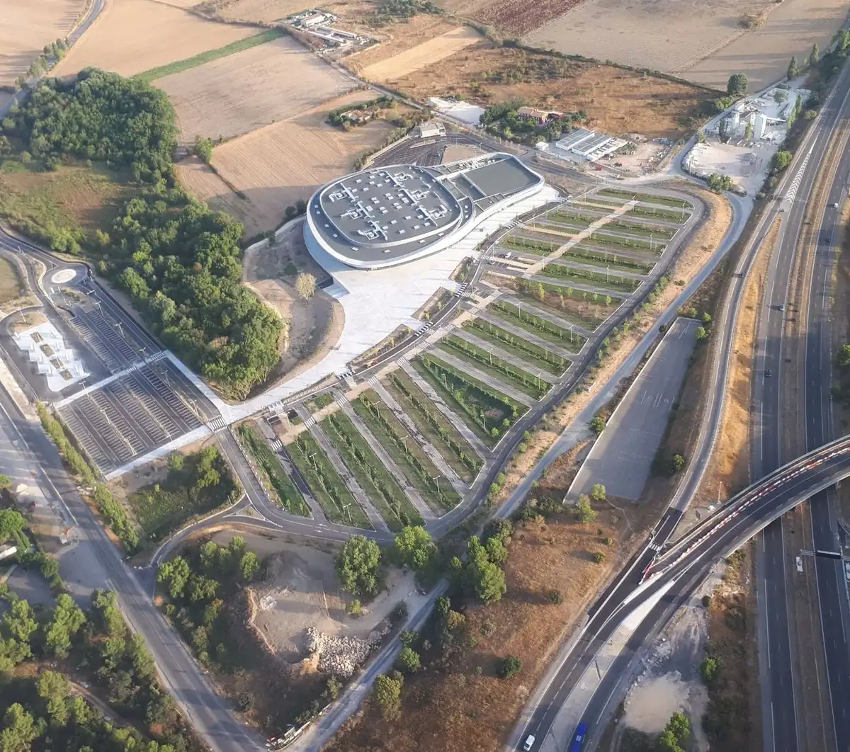 Vue aérienne réelle du parvis et de l'Arena : l'esplanade, les parkings, la Via et les accès
